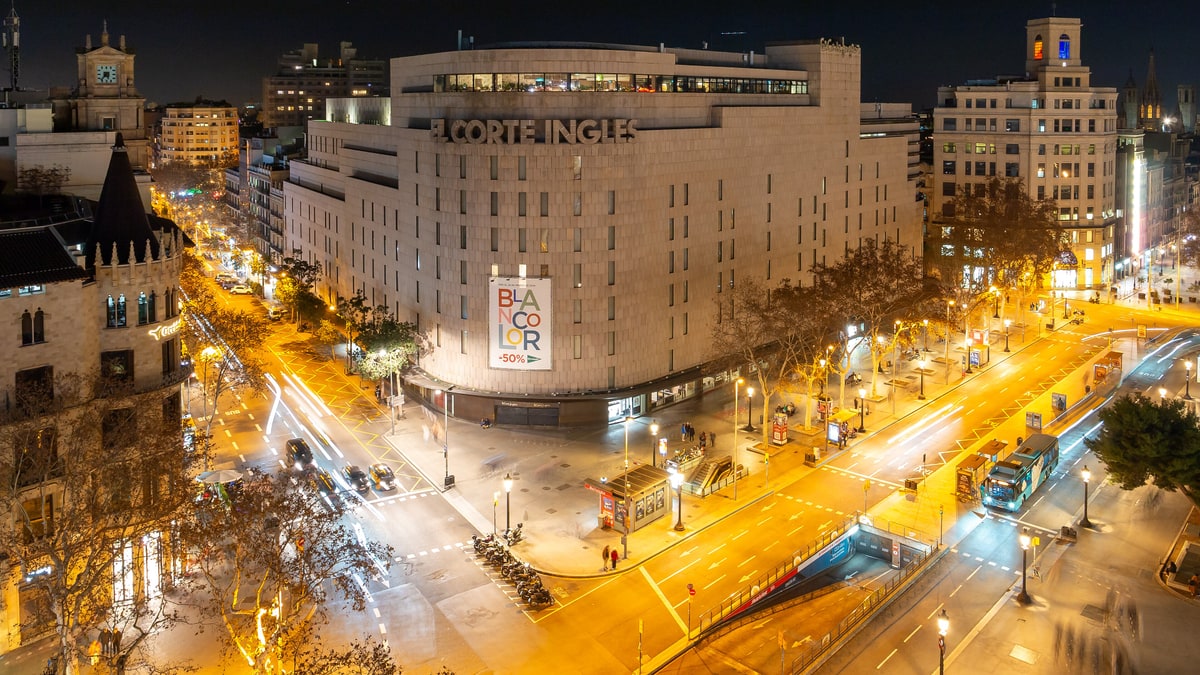 Vista nocturna de la plaça de Catalunya con El Corte Inglés iluminado y tráfico de luces