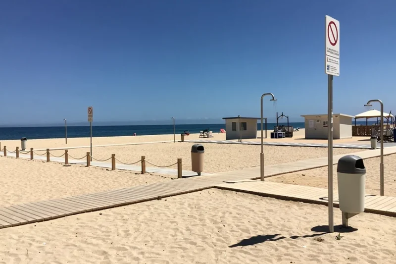 Vista panorámica de la playa de Mataró con instalaciones limpias y señalización sobre zonas libres de humo.